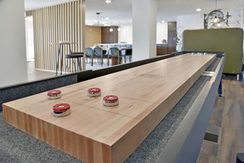 Close up of shuffleboard table with four discs on each side, community space in background